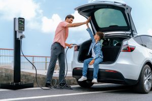 Father and son high fiving behind an electric car