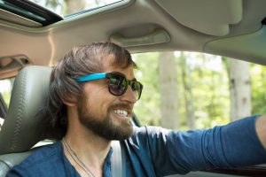 A man in sunglasses in the driving seat of a car.