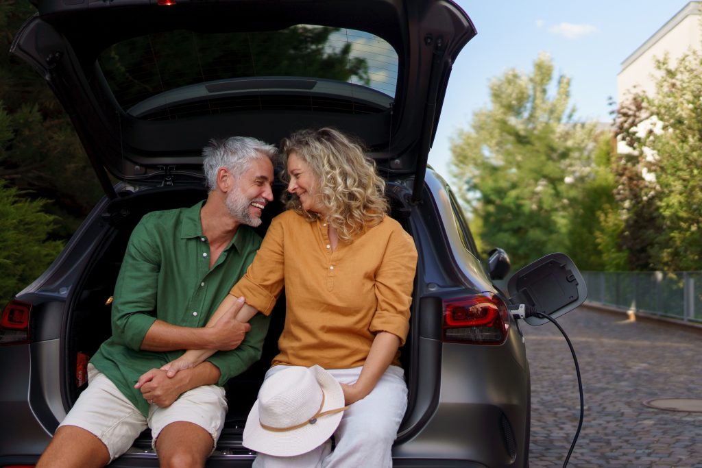 Older couple smiling, whilst their car is on charge